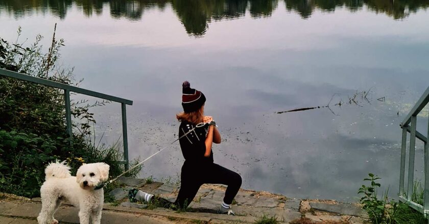 Junges Mädchen joggt mit ihrem Hund am Ufer des Rotter Sees in Troisdorf, umgeben von ruhiger Natur.