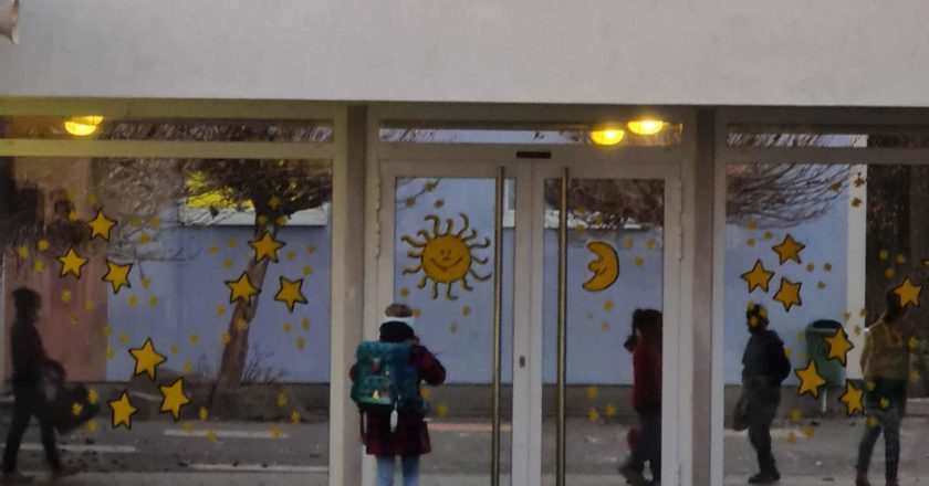 Schulkind mit Schulranzen vor einer Schule