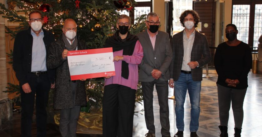 Manfred Piana und Till Schüler vom MAC, Oberbürgermeisterin Sibylle Keupen, Peter Loosen, Thomas Bremerich und Sundra Kisitu bei der Scheckübergabe im Aachener Rathaus.