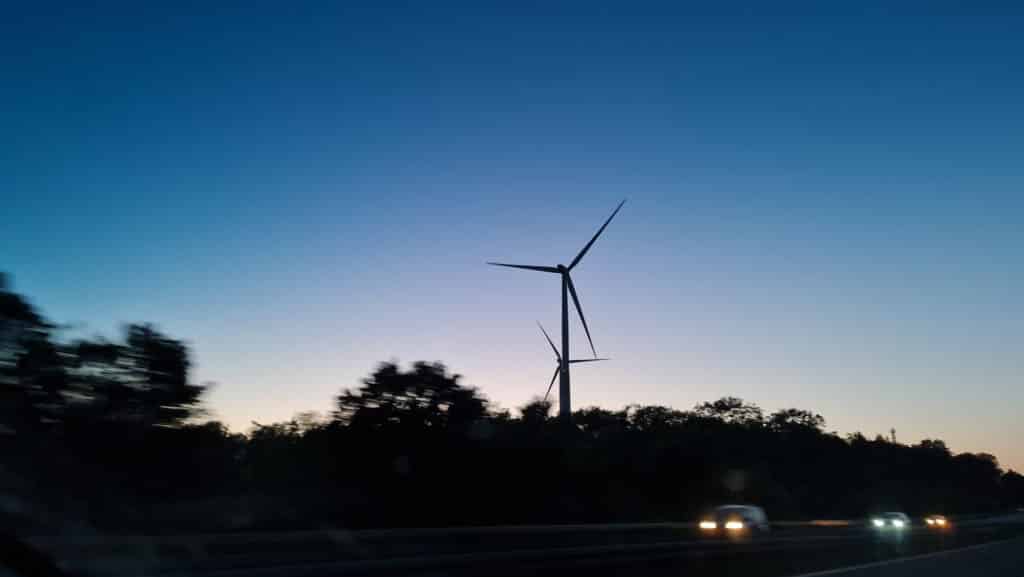 Das Foto zeigt Windräder und ein Wasserstoffauto