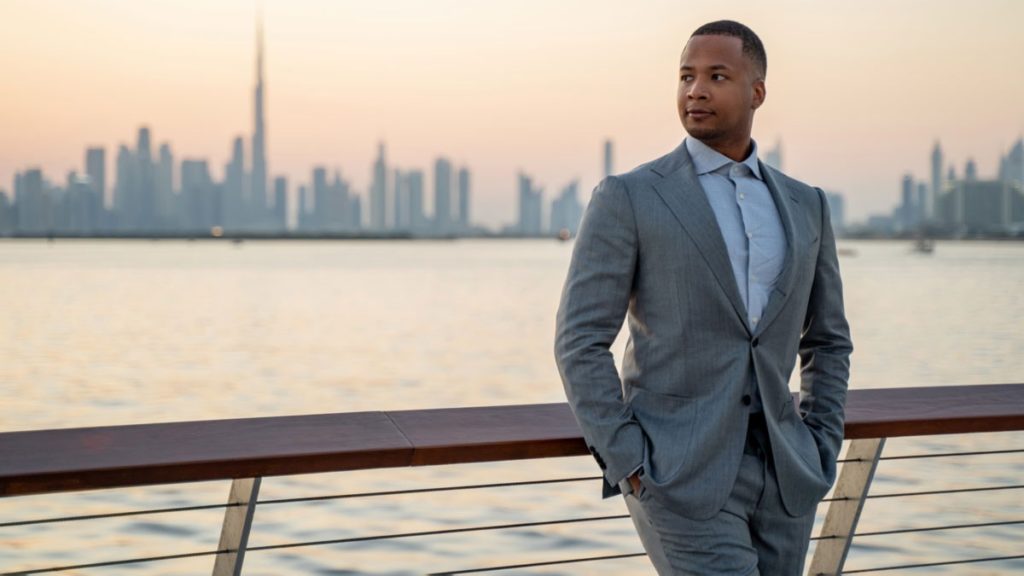 Jeffrey Oliver, Experte für Dubai, klärt acht gängige Gerüchte über die Stadt auf. Er lehnt an einem Geländer und im Hintergrund sind die Skyline von Dubai und das Wasser zu sehen. Das Foto ist Eigentum von Jeffrey Oliver.
