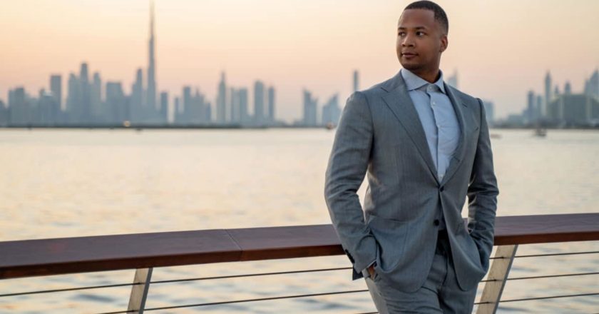 Jeffrey Oliver, Experte für Dubai, klärt acht gängige Gerüchte über die Stadt auf. Er lehnt an einem Geländer und im Hintergrund sind die Skyline von Dubai und das Wasser zu sehen. Das Foto ist Eigentum von Jeffrey Oliver.