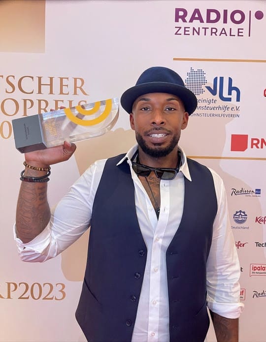 Reece“ Moore von bigFM mit dem Deutschen Radiopreis 2023 in der Hand, fotografiert von Julia Röttinger.