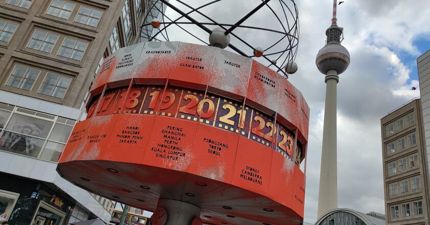 Aktivisten der 'Letzten Generation' sprühen orangerote Farbe auf die Weltzeituhr in Berlin und entrollen ein Protestbanner mit der Botschaft über den dringenden Klimawandel.