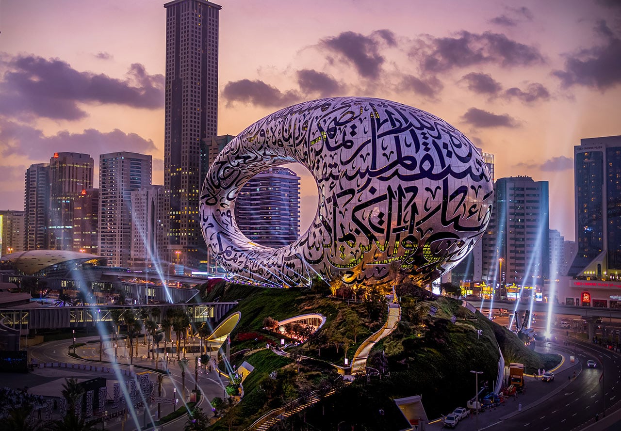 Das Foto zeigt das Museum der Zukunft in Dubai bei Dämmerung, umgeben von der Skyline der Stadt.