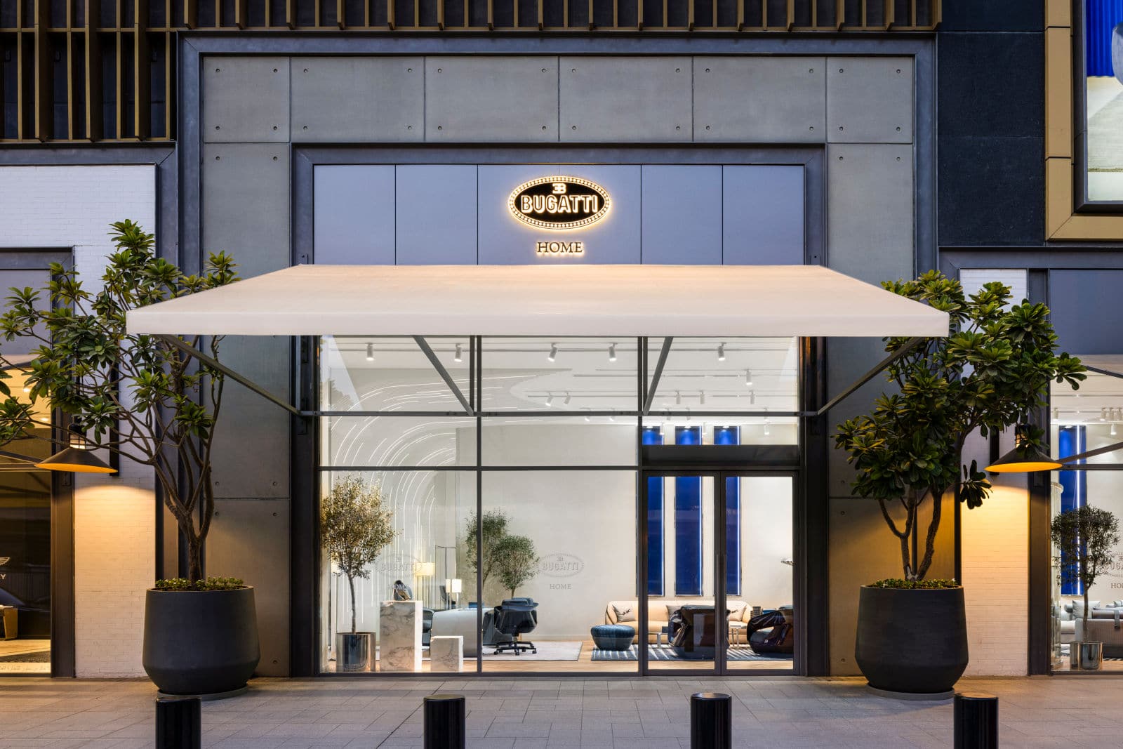 Die Außenansicht der weltweit ersten Bugatti Home Boutique in Dubai, mit eleganter Glasfassade, modernem Design und einem markanten Bugatti-Logo.