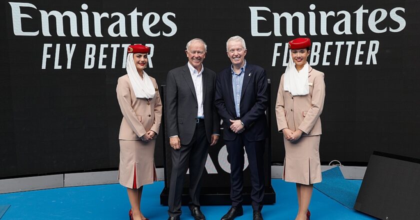 Das Foto zeigt Sir Tim Clark, Präsident Emirates Airline, und Craig Tiley, CEO Tennis Australia, in der Rod Laver Arena, flankiert von zwei Emirates-Flugbegleiterinnen in traditioneller Uniform.