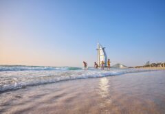 Familie genießt ihren Dubai Urlaub am Strand mit dem berühmten Hotel Burj al Arab im Hintergrund.