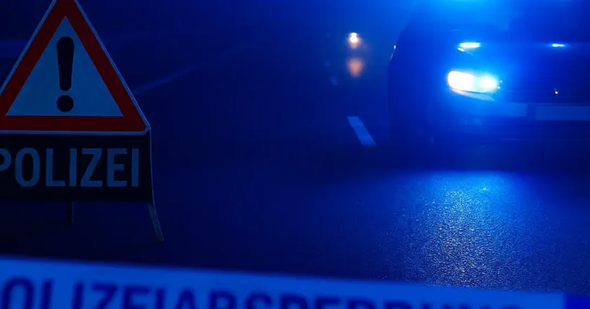 Symbolbild: Polizeifahrzeug mit Blaulicht und Absperrband bei nächtlicher Straßensperrung