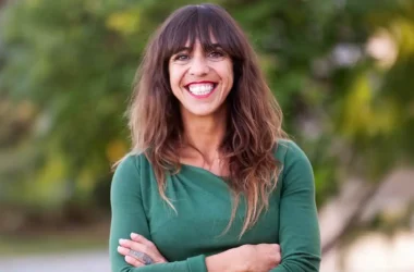Porträt von Virginia Pérez, Innenarchitektin und Möbeldesignerin auf Mallorca, lächelnd vor grünem Hintergrund.