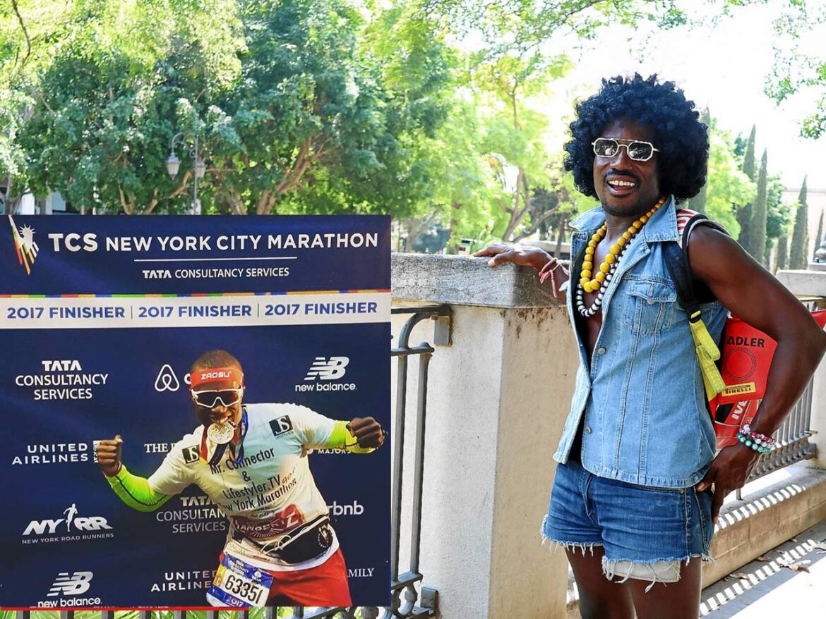 DJ NanaLove posiert lächelnd neben einem Finisher-Plakat des New York City Marathon 2017, im bunten Afro-Look mit Perücke, Ketten und Jeans-Outfit.