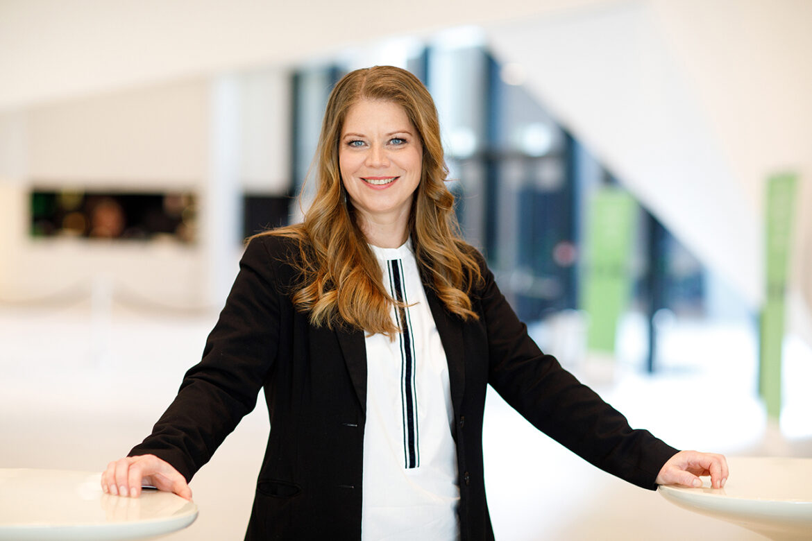 Natascha Müllauer, neue Verwaltungsdirektorin des Gürzenich-Orchester Köln, steht lächelnd in einem modernen Innenraum.