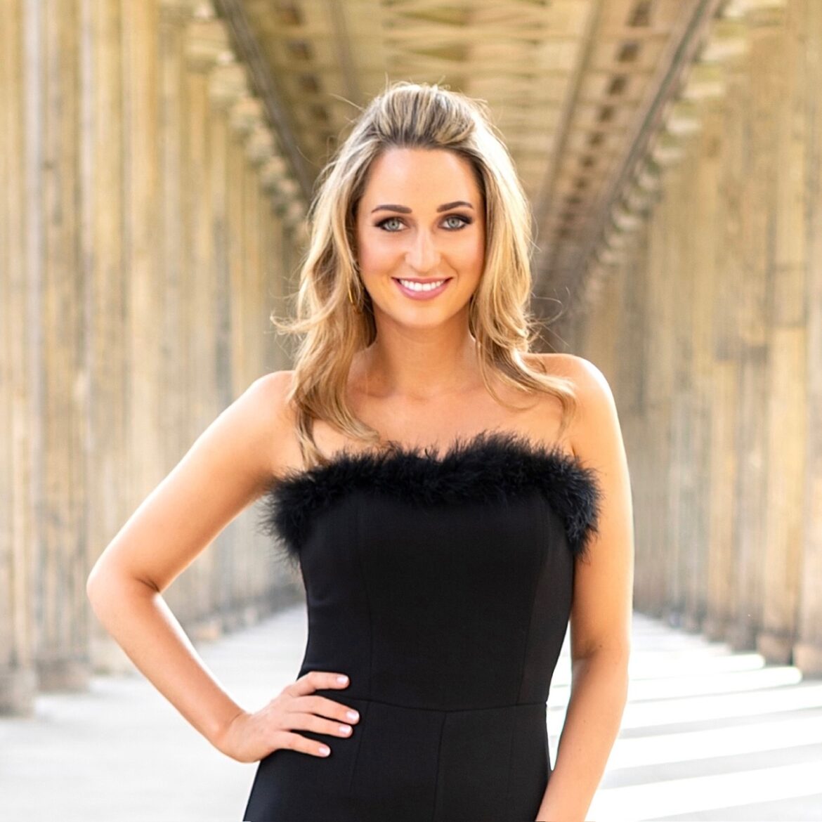 Madeline Willers im schwarzen trägerlosen Kleid bei einem Fotoshooting unter einer Säulenarchitektur