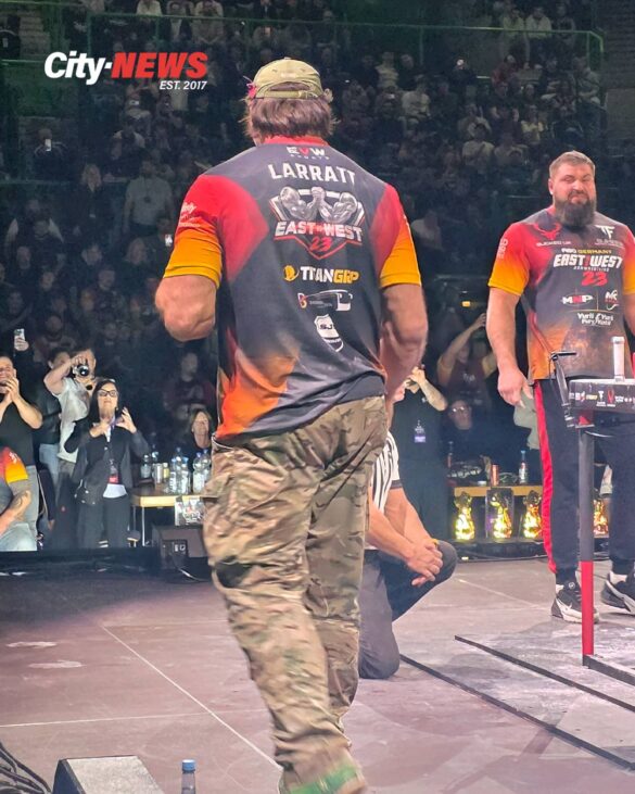 Devon Larratt approaches the table with the crowd rising behind him while Vitaly Laletin waits across the stage, capturing the scale and anticipation of the EVW 23 main event.