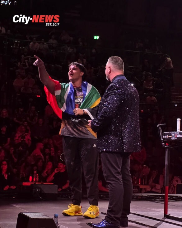 Duvan Bornman stands on stage during East vs West 23, wrapped in the atmosphere of the arena as the spotlight isolates him from the crowd behind.