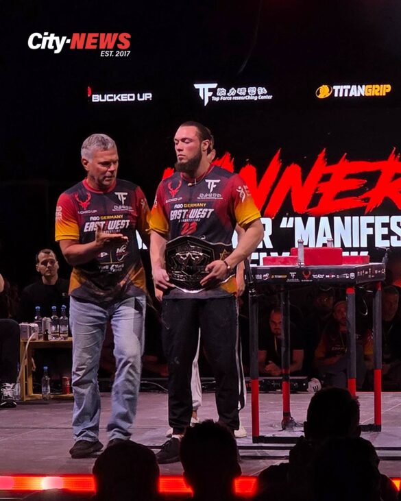 Oleksandr “Manifestor” Telyatnik stands on the East vs West 23 stage holding the Right Arm Welterweight World Title belt as John Brzenk congratulates him moments after the award ceremony.